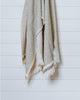 Beige and soft sage green Turkish waffle bath towel hanging neatly on white panel wall