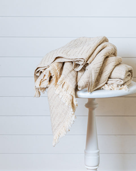 Heavy woven linen and Turkish cotton throw in sand color folded on wooden stool