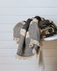 Black and sand Turkish cotton throw with grey accent folded on wooden stool