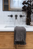 Taupe waffle-knit cotton hand towel draped over bathroom sink with wood cabinet