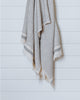 Beige and charcoal gray Turkish waffle bath towel hanging on white wood panel wall