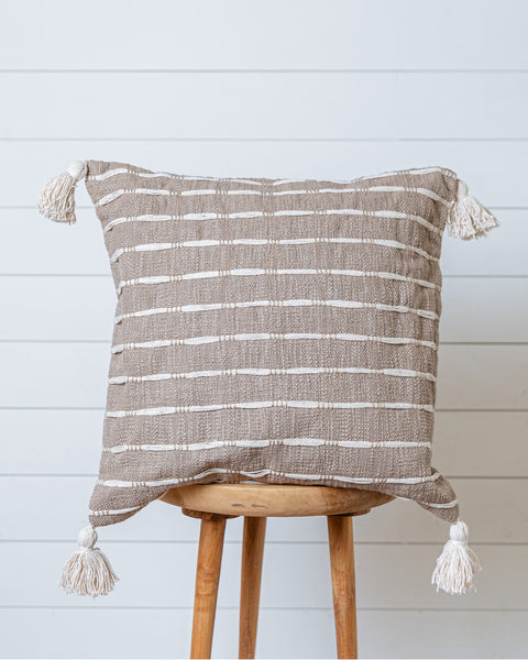 Taupe and ivory striped cotton cushion cover with tassels on wooden stool
