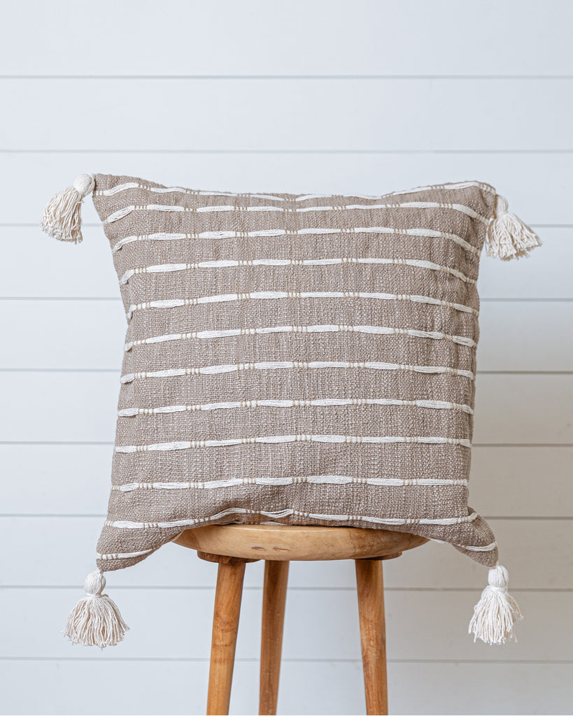 Taupe and ivory striped cotton cushion cover with tassels on wooden stool